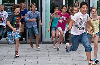 Viele Kinder stürmen aus der Schule.